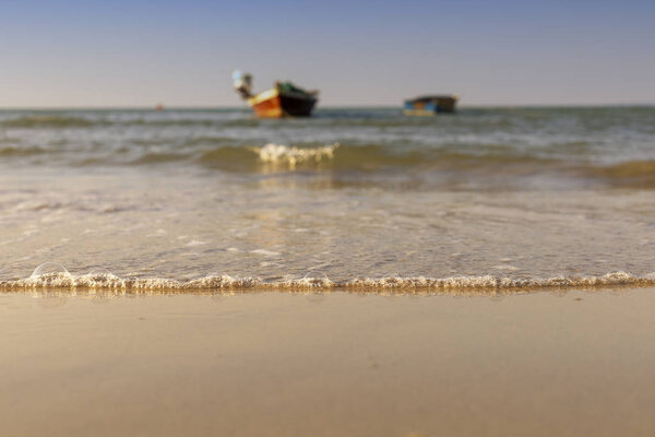 Soft wave from sea come to wet sand beach withblur boat and clear sky background. With copy space for text or design
