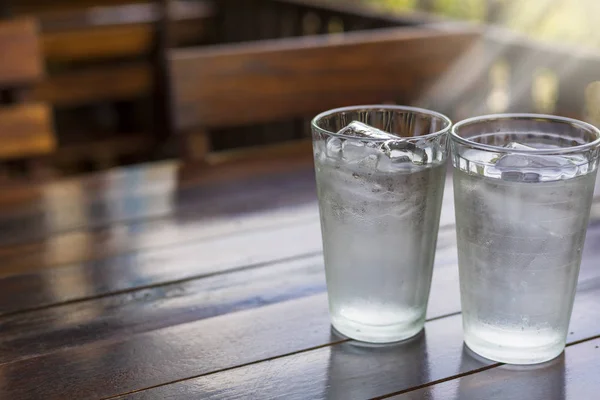 2 Bicchiere con ghiaccio e acqua fredda sul tavolo di legno . — Foto Stock