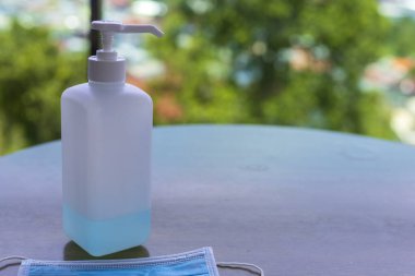 Coronavirus Covid-19 konsept yüz maskesi ve ahşap masa üzerinde alkol dezenfektanı jeli el yıkama.