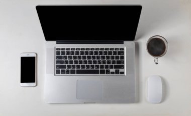 Üst görünüm dizüstü bilgisayar, fare, akıllı telefon, metin veya tasarım için telif alanı olan beyaz ahşap masadaki kahve.