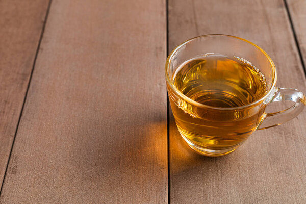Close up hot tea cup on wood table . hot tea in handle glass with copy space for text or design.