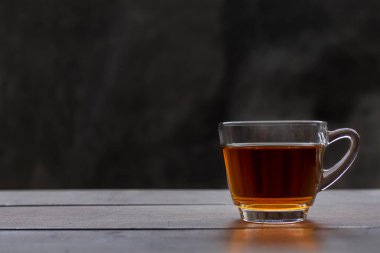 Tahta masadaki sıcak çay fincanını kapat. Metin veya tasarım için fotokopi alanı olan bir bardak sıcak çay. Ham harç arkaplanlı sıcak çay.