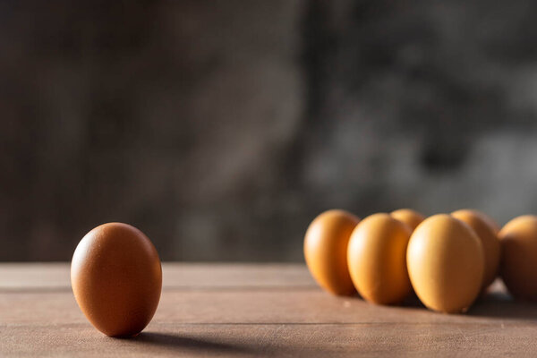 social distancing concept. Checken eggs have one chicken egg is far away from the group of chicken eggs.Interpret social distancing. One and group for chicken eggs on wood table .Soft focus and focus