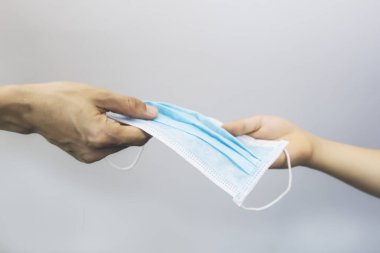 Kadınlar cerrahi maskeye el atarlar. Kadınlar virüsü korumak için tıbbi maske takarlar. Kopyalama alanı olan. Anne eli, ameliyat maskesine kız eliyle verir..