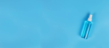 Mavi arka planda mavi alkol izole edilmiş. Temizlik için el dezenfektanı. Saç spreyi şişesinde el dezenfektanı. kopyalama alanı ile.