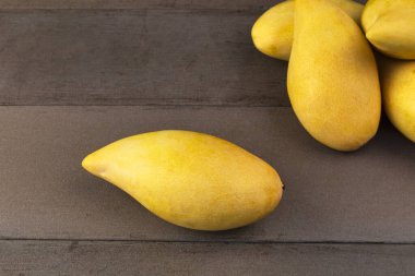 Sarı taze mangolar gerçek ahşap masa. Ahşap arka planda mango tropikal meyvesi. Metin veya tasarım için kopyalama alanı olan mangolar.