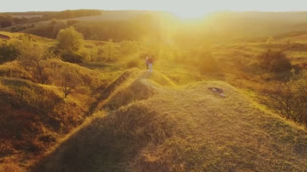 Casal jovem caminhando em direção ao pôr do sol — Vídeo de Stock