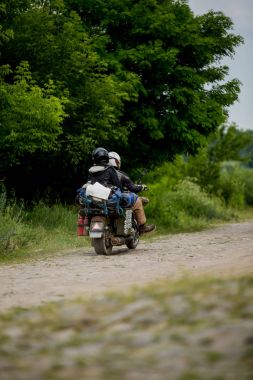 Man riding motorcycle with a woman on rural road. Young couple on motorbike through country road. Couple riding a motorcycle clipart