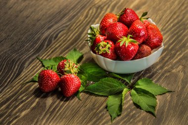 çilek ahşap bir masa üzerinde. çilek doku arka plan bir masada. Kase sulu taze olgun kırmızı çilek ile dolu. Taze çilek. Bir kase çilek