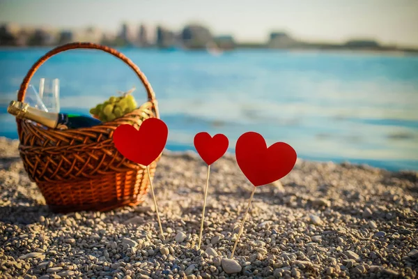 Picnic. champagne. picnic basket. Beautiful sea beach. Hearts on the beach stand on sticks. Valentines Day — Stock Photo, Image