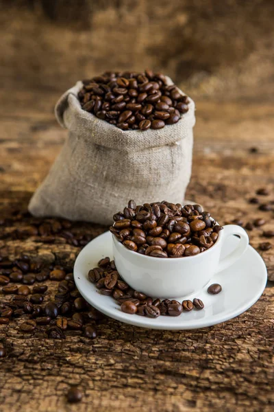 Coffee cup with coffee bag on wooden table. Coffee cup and coffee beans on a wooden table and sack background