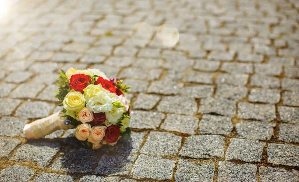 A wedding bouquet of roses of the bride lying on a stone. Wedding attributes. Bouquet of roses