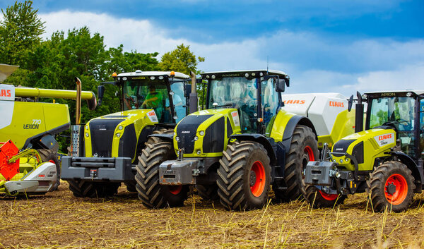 ВИННИЦА, УКРАИНА - ИЮЛЬ 2017: Тракторы и комбайны CLAAS. Сельскохозяйственное поле с посевами во время сбора урожая

