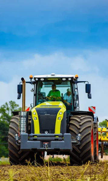Vinnitsa, Oekraïne - juli 2017. Een jonge boer op landbouwgrond met een tractor. Gebied van de landbouw met gewassen bij de oogst — Stockfoto