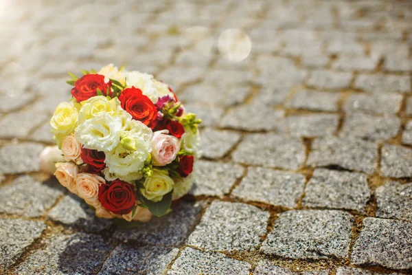 Um buquê de casamento de rosas vermelhas e brancas, encontra-se nas pedras antes da cerimônia de casamento . — Fotografia de Stock