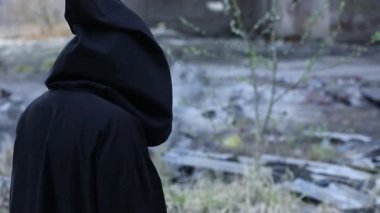 Gizemli kişi enkaz ve kül içinde yürüyüş