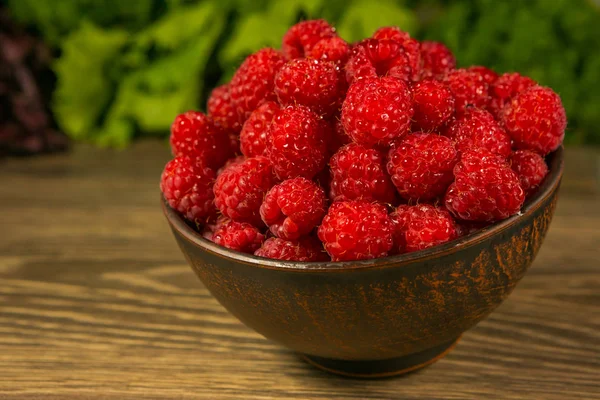 Full bowl of ripe raspberries on a wooden table — Stock Photo, Image