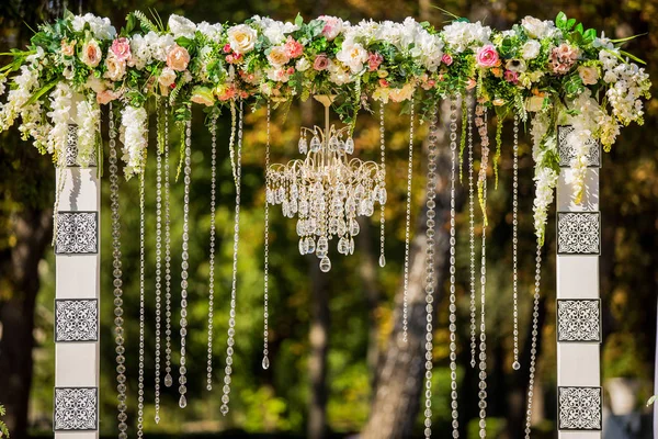 Arco para la ceremonia de boda. Decorado con araña de cristal y flores frescas. Decoraciones de boda. Los recién casados . — Foto de Stock