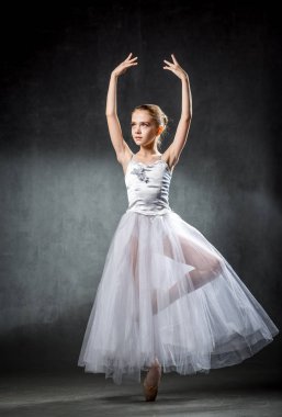 Genç ve inanılmaz güzel balerin poz ve ışığın tam bir stüdyoda dans. Fotoğrafçılığı büyük ölçüde klasik bale sanatının eşsiz güzelliğini yansıtan.