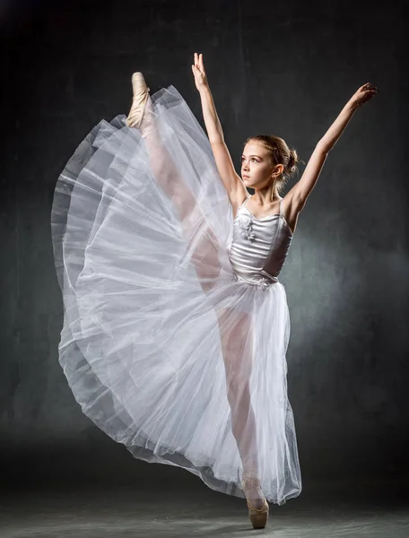 Genç kız balerin dans elemanları karanlık bir arka plan üzerinde gösterilen. Bale.