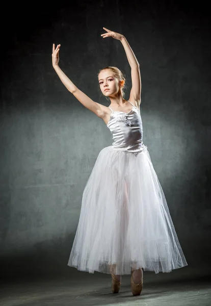 Vackra unga ballerina dansar i studion på en mörk bakgrund. En liten dansare. Balettdansös. — Stockfoto