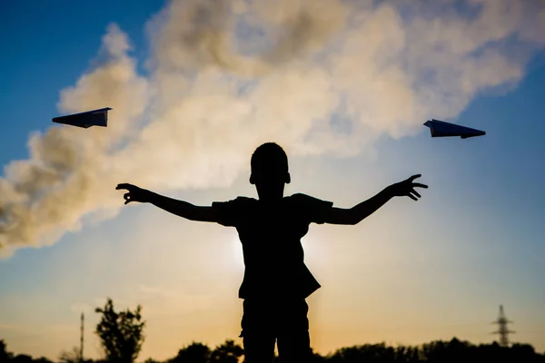 Мальчик бросает бумажный самолет на фоне дымящейся трубки. Экология . — стоковое фото