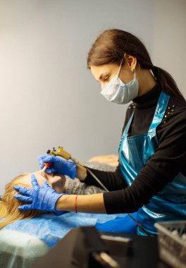 Kozmetik uzmanı kaşlarına kalıcı makyaj uyguluyor.