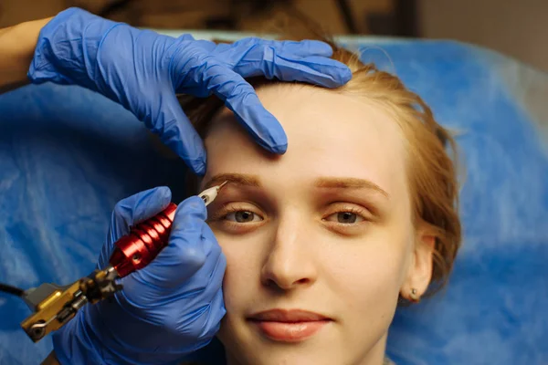 Cosmetoloog aanbrengen van permanente make-up op de wenkbrauw tatoeage — Stockfoto