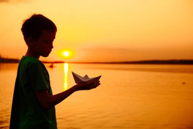 Kağıt tekne bir çocuk elimizde değil. Güzel yaz gün batımı. Origami
