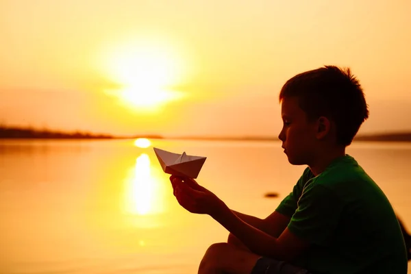 Papierboot ist in den Händen eines Kindes. schöner Sommersonnenuntergang. Origami — Stockfoto