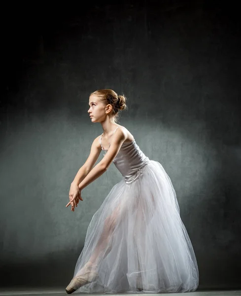 Vackra unga ballerina dansar i studion på en mörk bakgrund. En liten dansare. Balettdansös. — Stockfoto