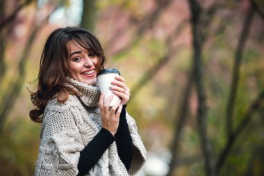 Bir fincan kahve sonbahar Park ile sıcak bir kazak güzel kız. Sıcak güneşli havalarda. Açık havada.