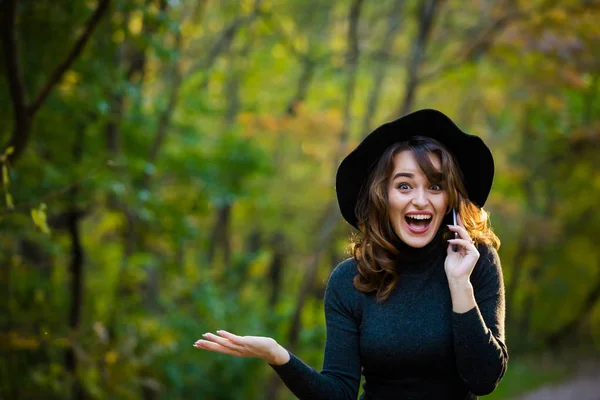 Retrato de una joven glamorosa con un sombrero negro. Autumn Park. Las emociones de las mujeres . — Foto de Stock