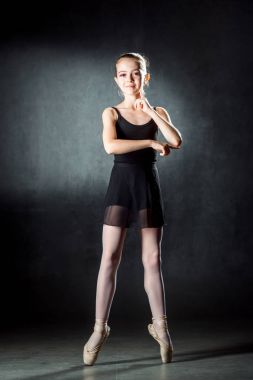 Bale. Esnek bir şirin balerin stüdyoda dans görüntüsü. Güzel genç dansçı. Küçük siyah elbise.