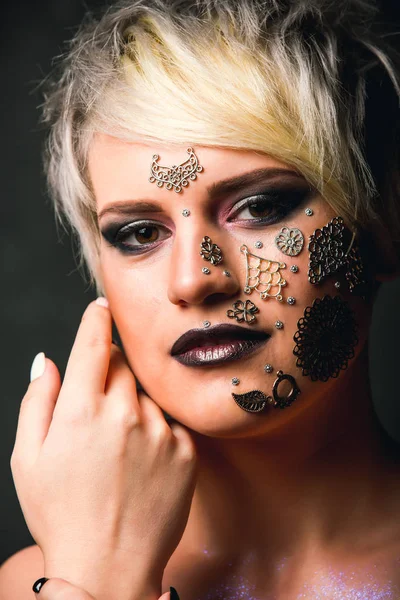 Retrato de uma mulher bonita com maquiagem criativa e penteado no estúdio. Jóias orientais na cara. Tendências de moda na maquiagem — Fotografia de Stock