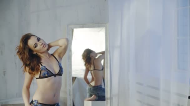 年轻性感的女人 穿着蓝色胸罩和时尚牛仔裤附近镜子摆姿势 — 图库视频影像