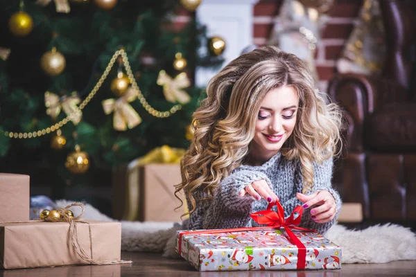 Oturma odasında yere yatan ne hediye kutusunda Noel ağacının yakınında olduğunu tahmin etmeye bir mutlu Noel kadın portresi. Kapat. — Stok fotoğraf