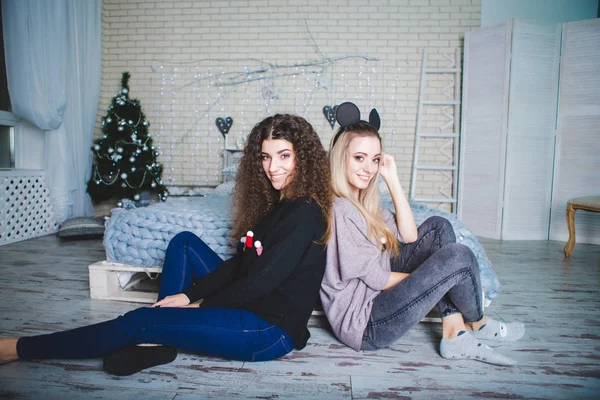 Portrait of two young women near a decorated Christmas tree. New Year's Eve. A bright festive image of two sisters. Merry Christmas — Stock Photo, Image