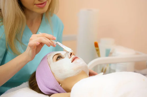 Frau erhält Gesichtsbehandlung von einem Kosmetologen in einem Wellnessbereich. Hautpflege. — Stockfoto