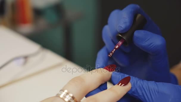 Frau im Salon erhält Maniküre von Nagelkosmetikerin. roter Nagellack.