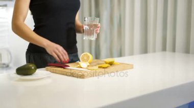Genç kadın mutfakta serinletici bir içki hazırlanıyor. Limonlu su. Sağlıklı bir yaşam tarzı. Suyu Detoks vitaminized.