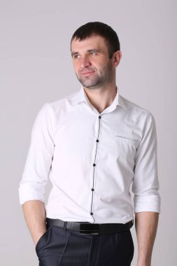 Elleri ceplerinde, beyaz arka plan üzerinde izole olan kendine güvenen genç yakışıklı adam