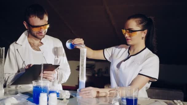 两位科学家在实验室工作 年轻的女研究员和她的高级主管正在调查试管 — 图库视频影像