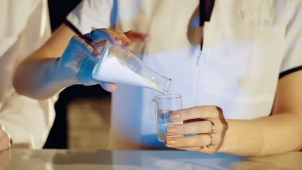 化学实验室的实验 年轻女子科学家混合试剂从玻璃烧瓶 — 图库视频影像