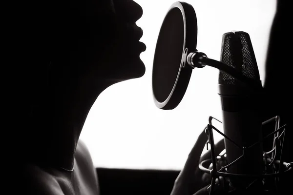 一个女人在录音棚里唱着歌的剪影。拉丁 — 图库照片