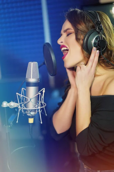 Primer plano de una chica con auriculares cantando una canción. Reco profesional —  Fotos de Stock