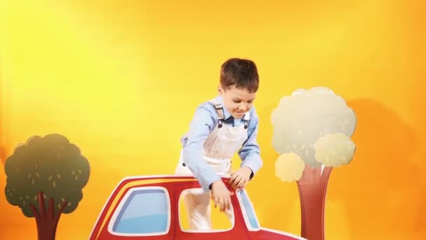 Niño Pequeño Con Coche Rojo Estudio Fondo Amarillo Escenario Brillante — Vídeos de Stock