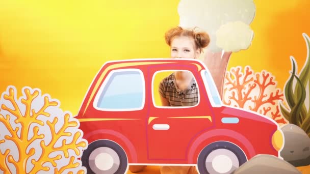 明るい黄色の壁の背景に面白い女の子 美しい子は大きなおもちゃの車で遊ぶ — ストック動画