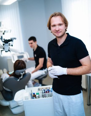 Dentist is posing to the camera at stomatology cabinet. Examining patient's teeth. Modern medical equipment. Oral care concept.