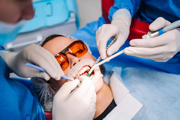Dentist in uniform perform dental treatment on a patient at modern stomatology office. Selective focus. View from the top. Closeup. — Stok fotoğraf